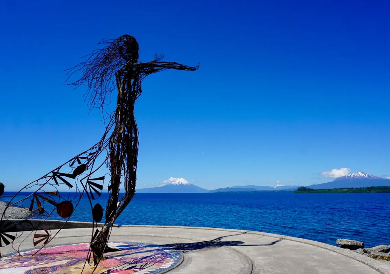 Escultura de alambre a orillas del lago con volcanes al fondo