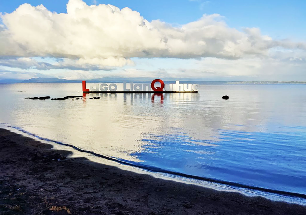 Letrero Lago Llanquihue reflejado en la orilla al atardecer